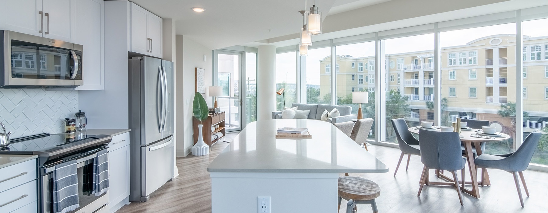 Spacious and well lit kitchen with wood floors and stainless steel appliances. 